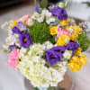 Colorful bouquet with purple, yellow, pink, and white flowers in a glass vase