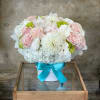 Pink and white flower arrangement in a white box with a blue ribbon