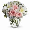 Pink roses and white lilies in a clear glass vase