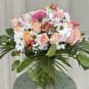Bouquet of peach roses and white daisies in a glass vase