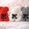 Three rose-covered teddy bears in red, white, and gray with black ribbons
