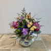 Pink and purple flowers arranged in a floral teapot with butterfly picks