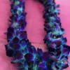 Purple and blue floral lei on a pink background