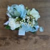 A petite wristlet-style corsage arranged with roses and clusters of tiny filler