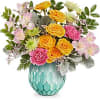 Mixed bouquet of yellow roses, pink carnations, and pale flowers in a turquoise vase