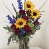 A custom designed arrangement, bright and beautiful design, includes cheerful seasonal blooms