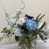 Mixed bouquet in a clear glass vase with blue hydrangea, white blooms, and purple tulips