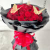 Bouquet of red roses wrapped in black paper with a pink ribbon