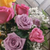 Bouquet of pink and lavender roses with white baby's breath and a yellow calla lily