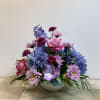 This garden-style floral arrangement offers a cohesive color palette of blues, purples