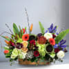 Mixed floral arrangement in a wooden box with bright blooms and branches