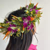 Tropical flower crown with purple orchids and orange accents on a person's head