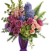 Mixed bouquet of roses, snapdragons, and purple blooms in a purple vase