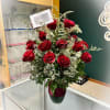 Red roses arranged in a vase with baby's breath and greenery