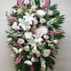 Tall standing spray of white lilies and mums with pink roses on a metal easel