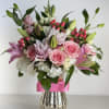 Pink roses and lilies in a silver vase with a pink ribbon