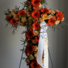 A bold cross-shaped standing spray crafted for memorial and funeral services, covered
