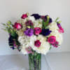Bouquet of white hydrangeas and pink and purple roses in a glass vase