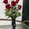 Red roses arranged in a black vase with white baby's breath