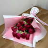 Bouquet of red roses wrapped in pink and white paper with a ribbon