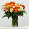 Orange and pink mixed bouquet in a clear glass vase