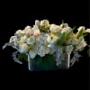 A low, rectangular centerpiece of pure white blooms creates an instant atmosphere