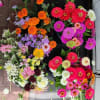 Assorted colorful flower bunches with zinnias and marigolds laid out on a dark surface