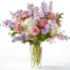 Tall glass vase of pink roses, white hydrangeas, and lavender stock flowers