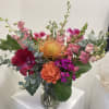 Bright mixed arrangement of orange and pink blooms in a clear glass vase