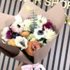 A rounded hand-tied bouquet of anemone, ranunculus, tulips and daisy-like blooms in