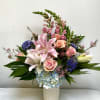 Large pink-and-white lilies take center stage in this flower arrangement, making it