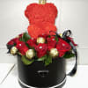 Red rose arrangement in a black round box with a small crown topper