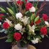 A striking sympathy arrangement featuring red and white blooms, graceful lilies, and