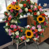 A vibrant sunflower wreath accented with roses, carnations, and seasonal blooms. 