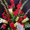 A striking tribute featuring red gladiolus, white lilies, and lush greenery.