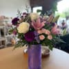 Soft pink lilies and creamy white roses curl above clusters of blush