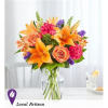 Bouquet of orange lilies, peach roses, and pink carnations in a glass vase