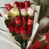 Bouquet of red and pale pink roses wrapped in white paper with a red bow