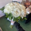 A compact, rounded hand-tied wedding bouquet of pure white roses-the kind of