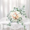 A pale, romantic wedding bouquet of blush roses and ivory ranunculus that