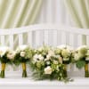 Soft cream roses, airy white hydrangeas, and daisy-like blooms are arranged in