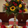 Tall and celebratory, this table arrangement for special events mixes sunflowers, roses