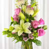 Soft pink roses and pale lilies rise above a cloud of creamy