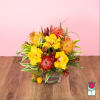 Tropical bouquet with yellow orchids and orange pincushion blooms in a glass vase