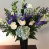 White roses and blue hydrangeas with purple irises in a tall vase