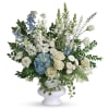 White and blue floral arrangement in a white urn vase
