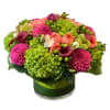 Bright mixed bouquet in a glass vase with pink, coral, and green blooms