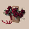 Deep burgundy roses tucked into a kraft paper gift bag create an