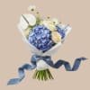 A large blue hydrangea takes center stage in this wrapped bouquet, making