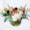 Mixed bouquet of blush and white flowers in a glass vase